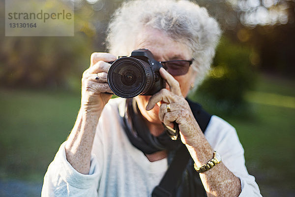 Nahaufnahme einer älteren Frau  die im Park durch eine Kamera fotografiert