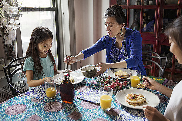 Hochwinkelansicht einer Mutter  die ihre Tochter beim Frühstück bedient