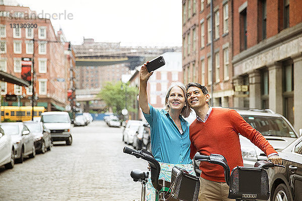 Ein erwachsenes Paar  das Selbsthilfe nimmt  während es mit Fahrrädern auf der Straße in der Stadt steht