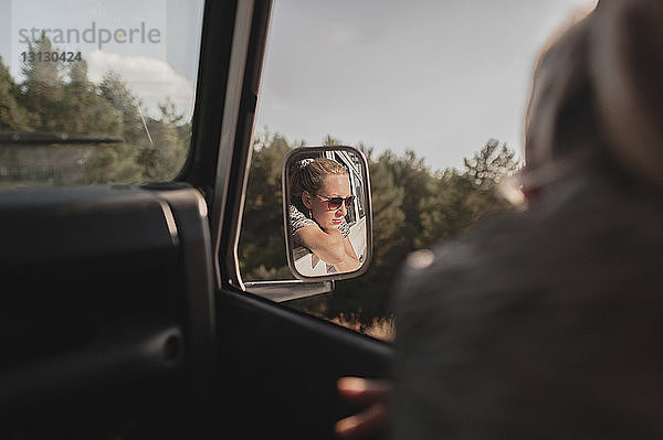 Spiegelung einer Frau im Seitenspiegel eines Autos