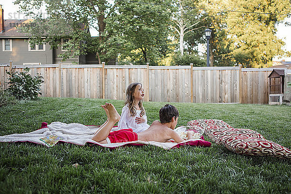Geschwister entspannen sich im Hinterhof auf einer Decke
