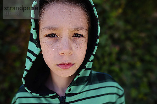 Porträt eines selbstbewussten Jungen mit Kapuze im Park