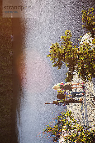 Hochwinkelaufnahme von Freunden  die auf einem Felsen am See stehen