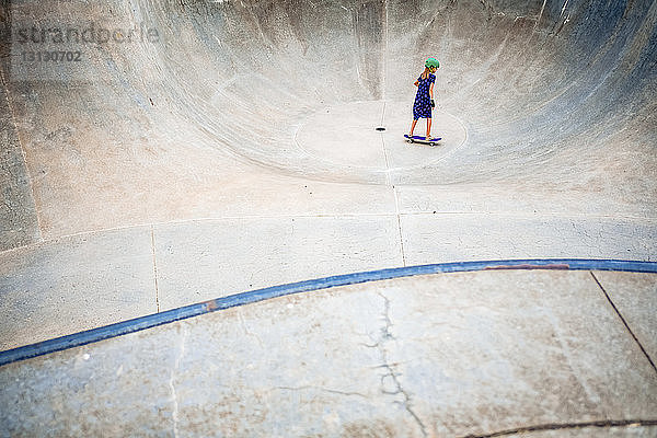 Hochwinkelaufnahme eines Skateboard fahrenden Mädchens auf einer Sportrampe im Park