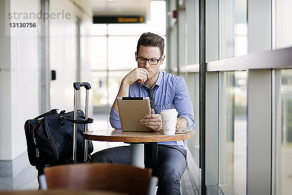 Geschäftsmann arbeitet am Tablet-Computer  während er in der Cafeteria der U-Bahn-Station sitzt
