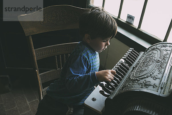 Hochwinkelaufnahme eines Jungen  der zu Hause ein Musikinstrument spielt