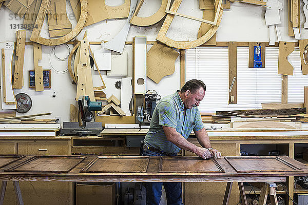Zimmermann poliert Holz während der Arbeit in der Werkstatt