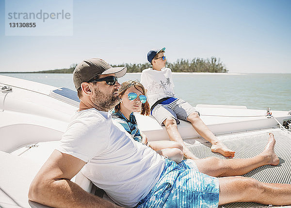 Familie entspannt sich im Boot auf dem Meer bei klarem Himmel am sonnigen Tag