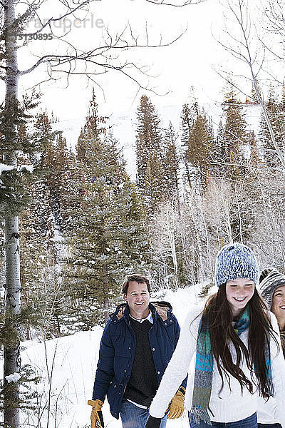 Familie geht im verschneiten Wald gegen den Himmel