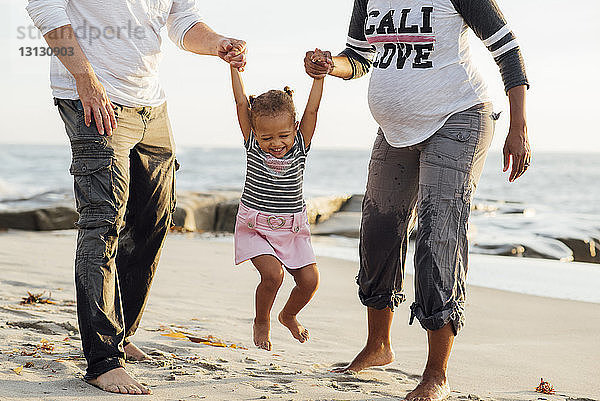 Niedriger Anteil von Eltern  die mit ihrer Tochter bei Sonnenuntergang am Strand spielen