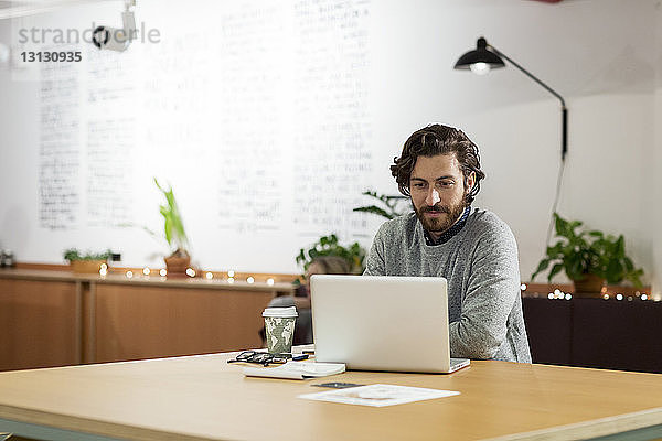 Geschäftsmann mit Laptop-Computer am Tisch im Büro