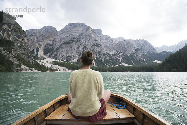 Rückansicht einer Frau  die in einem Boot auf einem Fluss inmitten eines Berges gegen den Himmel sitzt