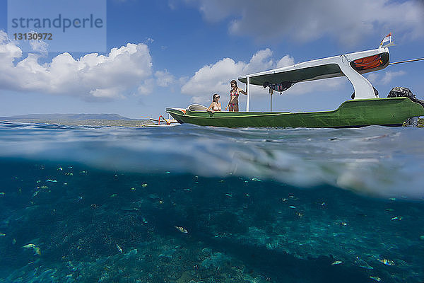 Wasseroberflächenbild von Freundinnen im Boot auf dem Meer gegen den Himmel