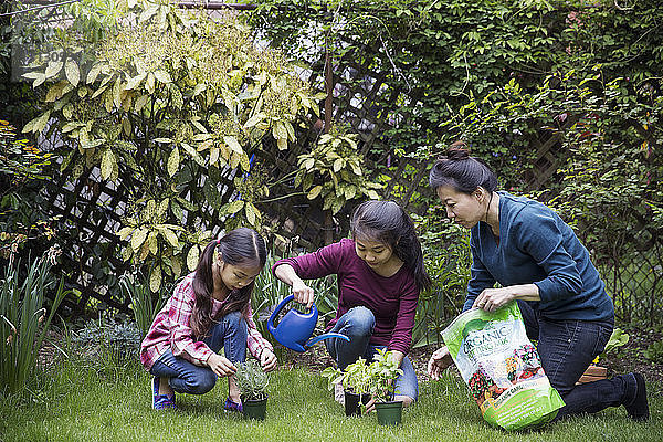 Mutter hilft Töchtern bei der Gartenarbeit im Hof
