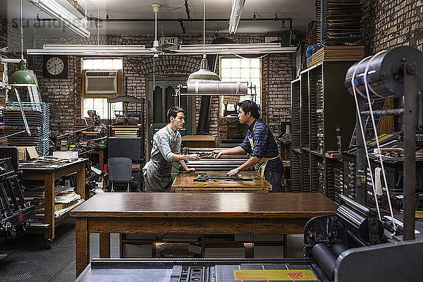 Seitenansicht der Arbeiter  die in der Werkstatt am Buchdruck arbeiten