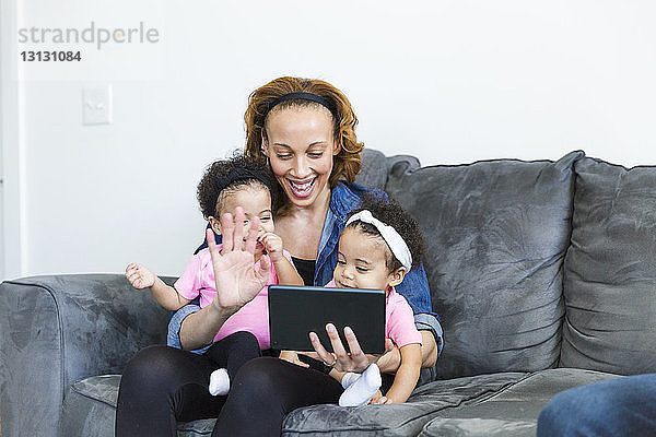 Glückliche Mutter und Töchter bei Videokonferenzen am Tablet-Computer