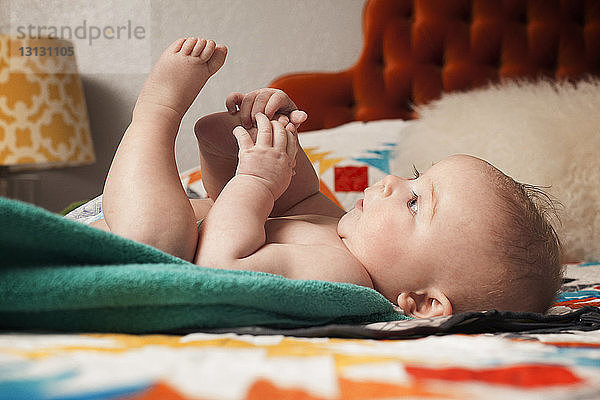 Verspieltes Baby im Bett zu Hause