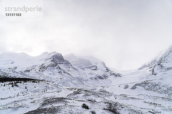 Tiefwinkelansicht eines schneebedeckten Berges gegen den Himmel bei nebligem Wetter