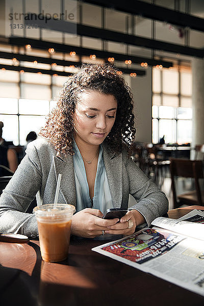 Geschäftsfrau benutzt Smartphone am Café-Tisch