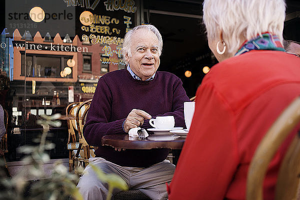 Nachdenklicher älterer Mann sitzt mit Frau im Bürgersteig-Café