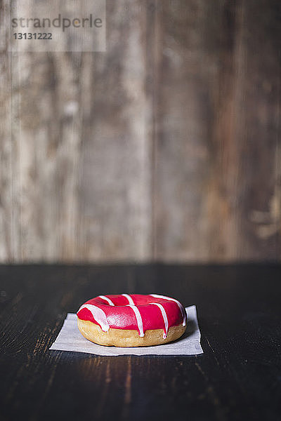 Nahaufnahme eines Donuts mit Wachspapier auf Holztisch