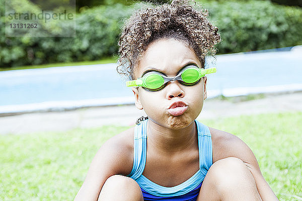 Verspieltes Mädchen kräuselt sich beim Tragen einer Schwimmbrille gegen den See