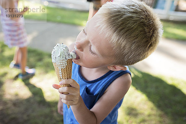 Junge leckt schmelzendes Eis  während er im Hinterhof steht