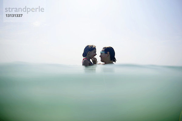 Mutter und Tochter im Meer gegen den Himmel