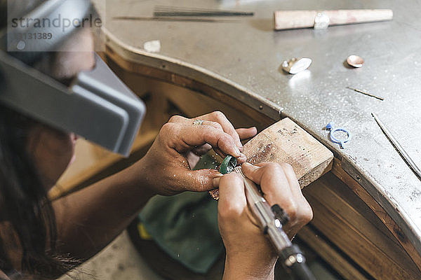 Hochwinkelansicht eines weiblichen handwerklichen Formringes mit Ausrüstung auf dem Tisch in der Werkstatt