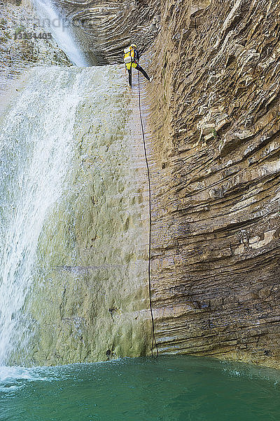 Tiefwinkelansicht einer Frau  die am Wasserfall auf einen Berg klettert