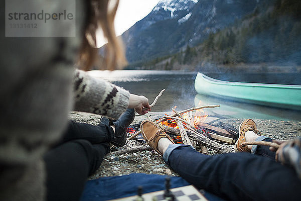 Niedriger Teil des Paares sitzt am brennenden Lagerfeuer im Silver Lake Provincial Park