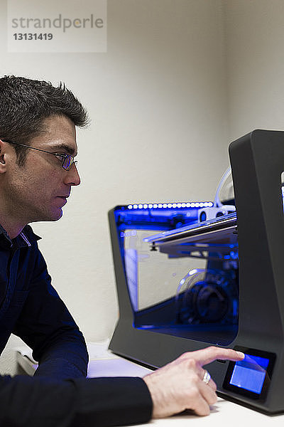 Ingenieur bedient 3D-Drucker auf Tisch im Büro