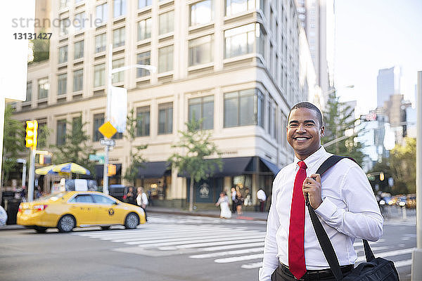 Porträt eines selbstbewussten Geschäftsmannes mit Tasche auf der Straße der Stadt stehend