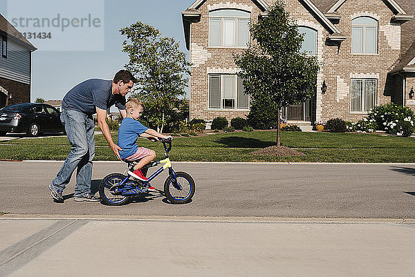 Vater hilft Sohn beim Fahrradfahren auf der Straße