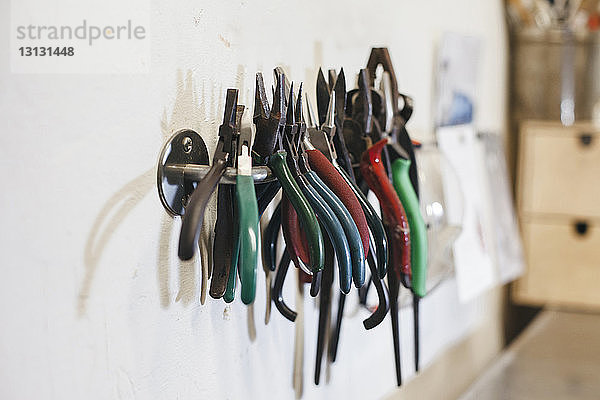 Nahaufnahme von bunten Zangen  die in der Werkstatt an einem Gestell an der Wand hängen