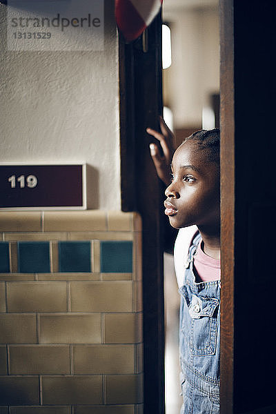 Nachdenkliches Mädchen steht in der Schule an der Tür