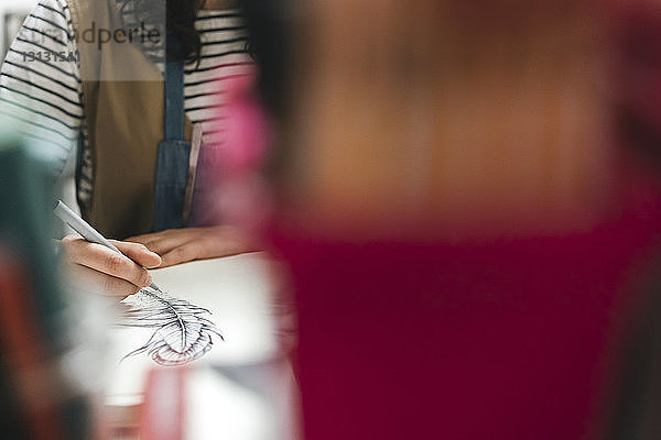 Mitten in der Werkstatt einer Kunsthandwerkerin  die auf einem Buch zeichnet