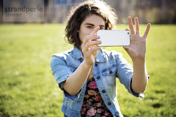 Frau fotografiert durch Smartphone auf Grasfeld