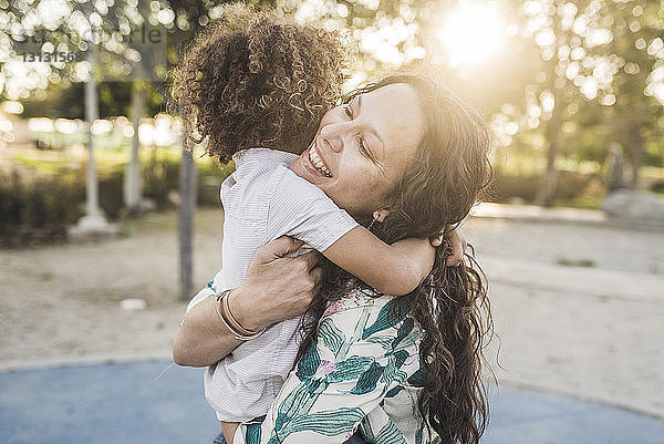 Lächelnde Mutter umarmt Sohn im Park