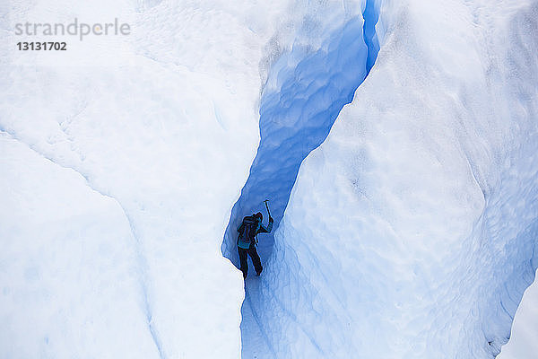 Niedrigwinkelansicht eines Mannes  der einen schneebedeckten Berg besteigt