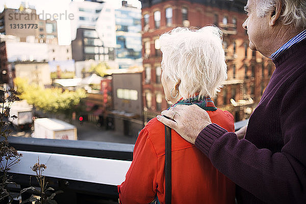 Älteres Ehepaar betrachtet die Stadtansicht  während es auf dem Balkon steht