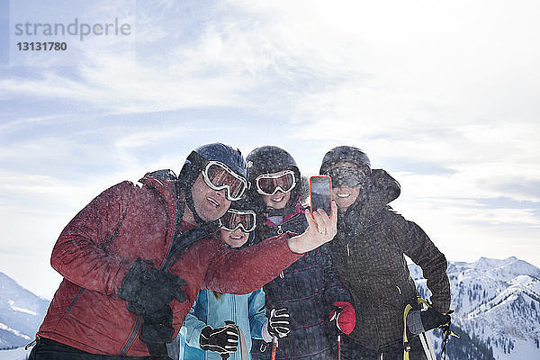 Familie nimmt Selfie mit Smartphone  während sie am Skiberg steht