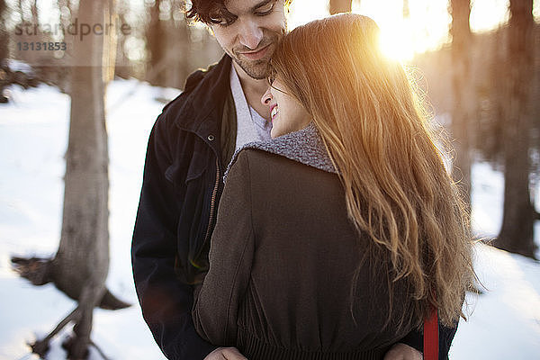 Rückansicht einer glücklichen Frau  die den Mann im Winter umarmt