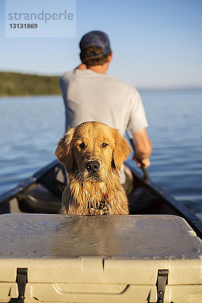 Porträt eines Hundes mit einem Mann  der in einem Boot auf einem See im Grand-Teton-Nationalpark unterwegs ist