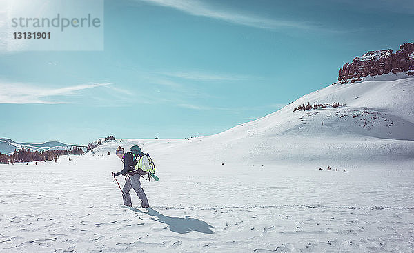 Seitenansicht einer Wanderin beim Wandern in verschneiter Landschaft