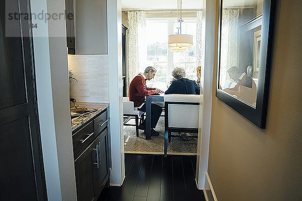 Älteres Ehepaar sitzt im Büro des Finanzberaters und wird durch die Tür gesehen