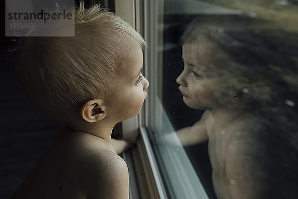 Hochwinkelaufnahme eines Jungen  der zu Hause am Fenster sitzt