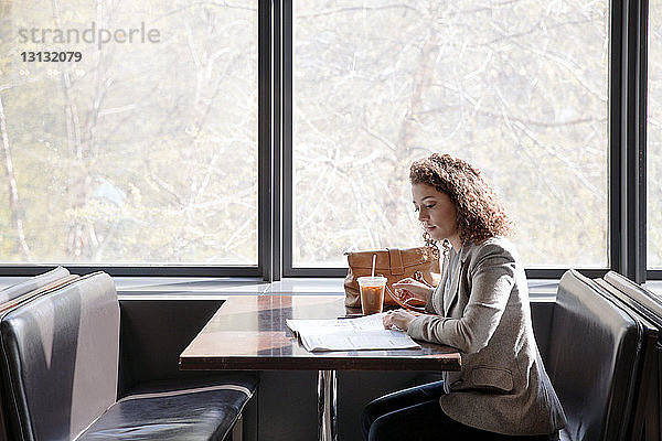 Seitenansicht einer Geschäftsfrau beim Lesen einer Zeitschrift im Cafe