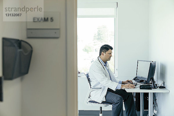 Seitenansicht eines Arztes bei der Arbeit im Krankenhaus am Desktop-Computer
