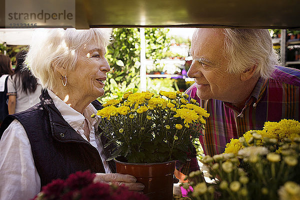 Glückliches älteres Ehepaar kauft Blumen auf dem Straßenmarkt